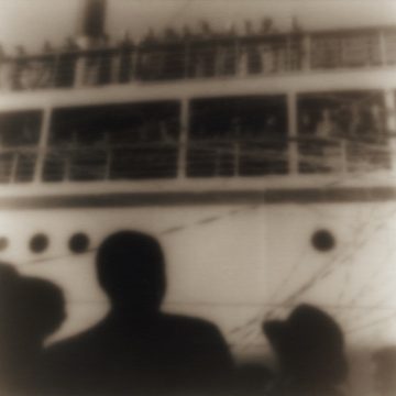 Silhouetted figures at port watching passengers on cruise ship depart.