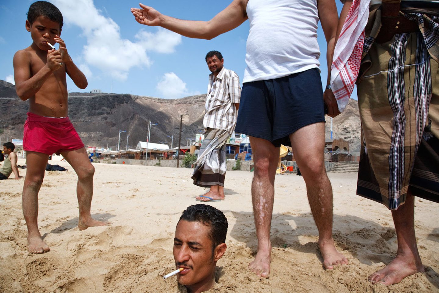 A man buried in the sand on the beach in Aden, Yemen.